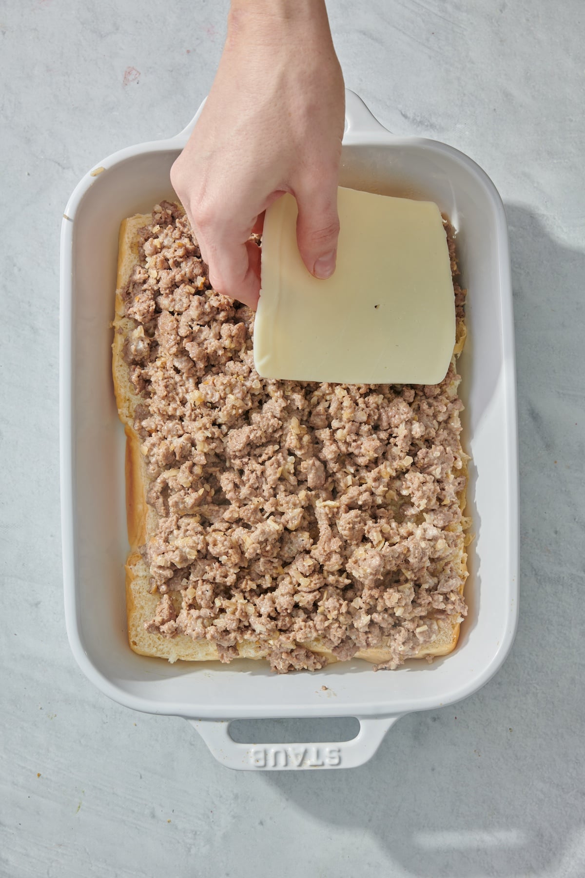 Placing cheese on top of ground beef.