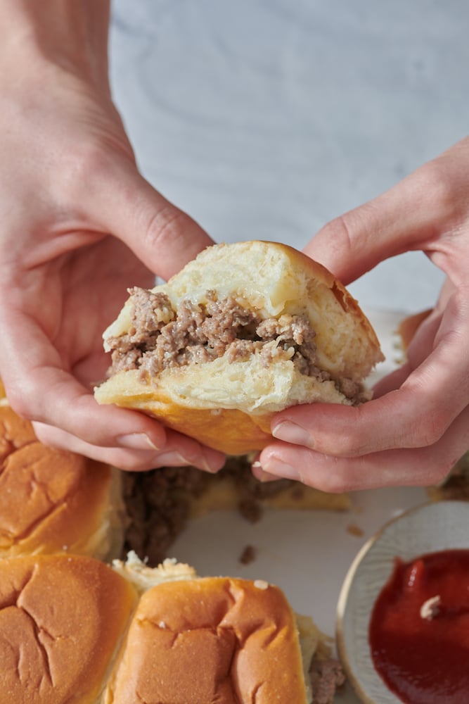 Hands holding easy cheeseburger slider.