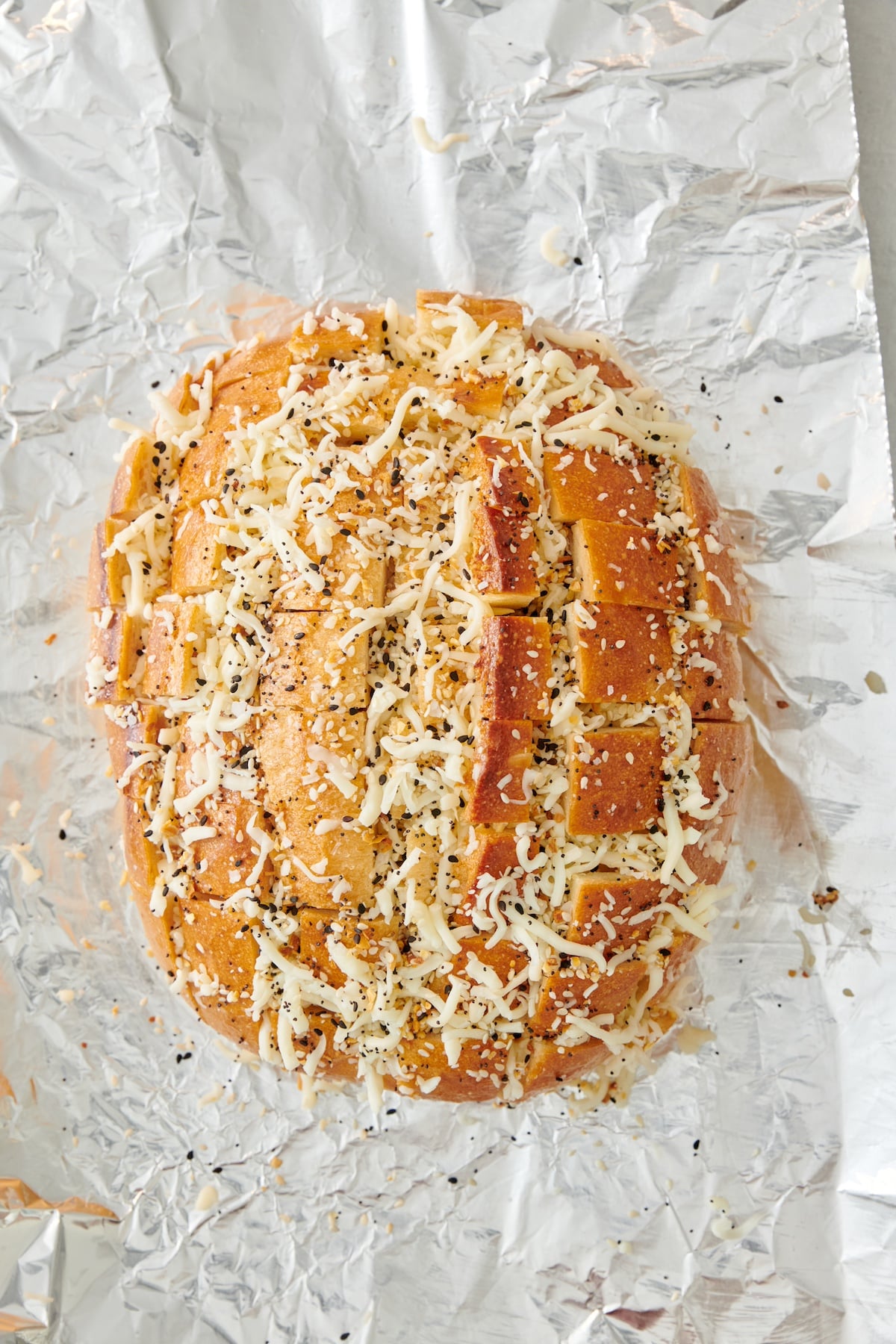 Loaf of bread with cheese, butter and everything seasoning in the grooves.