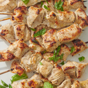 Chicken tikka skewers topped with cilantro.