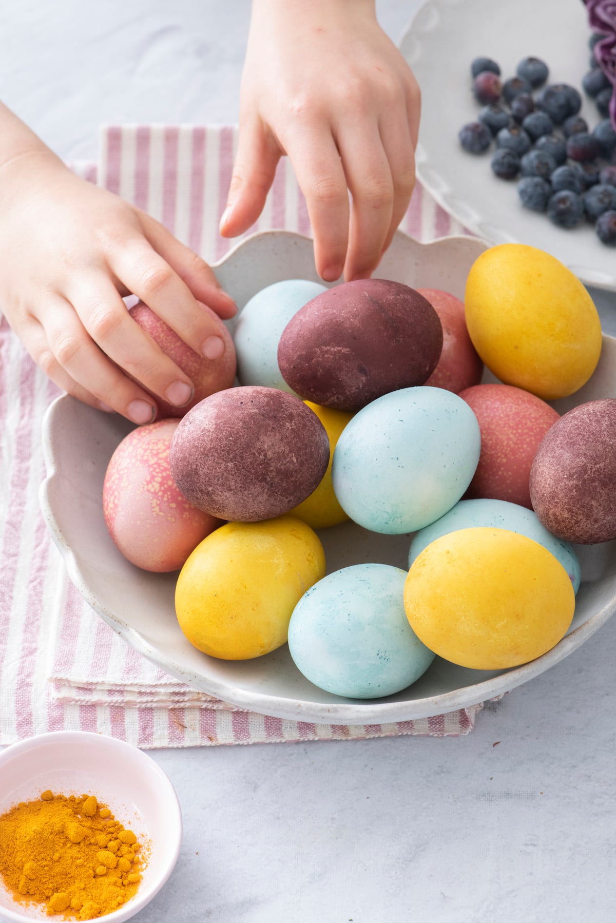 child's hand grabbing dyed eggs from a pile