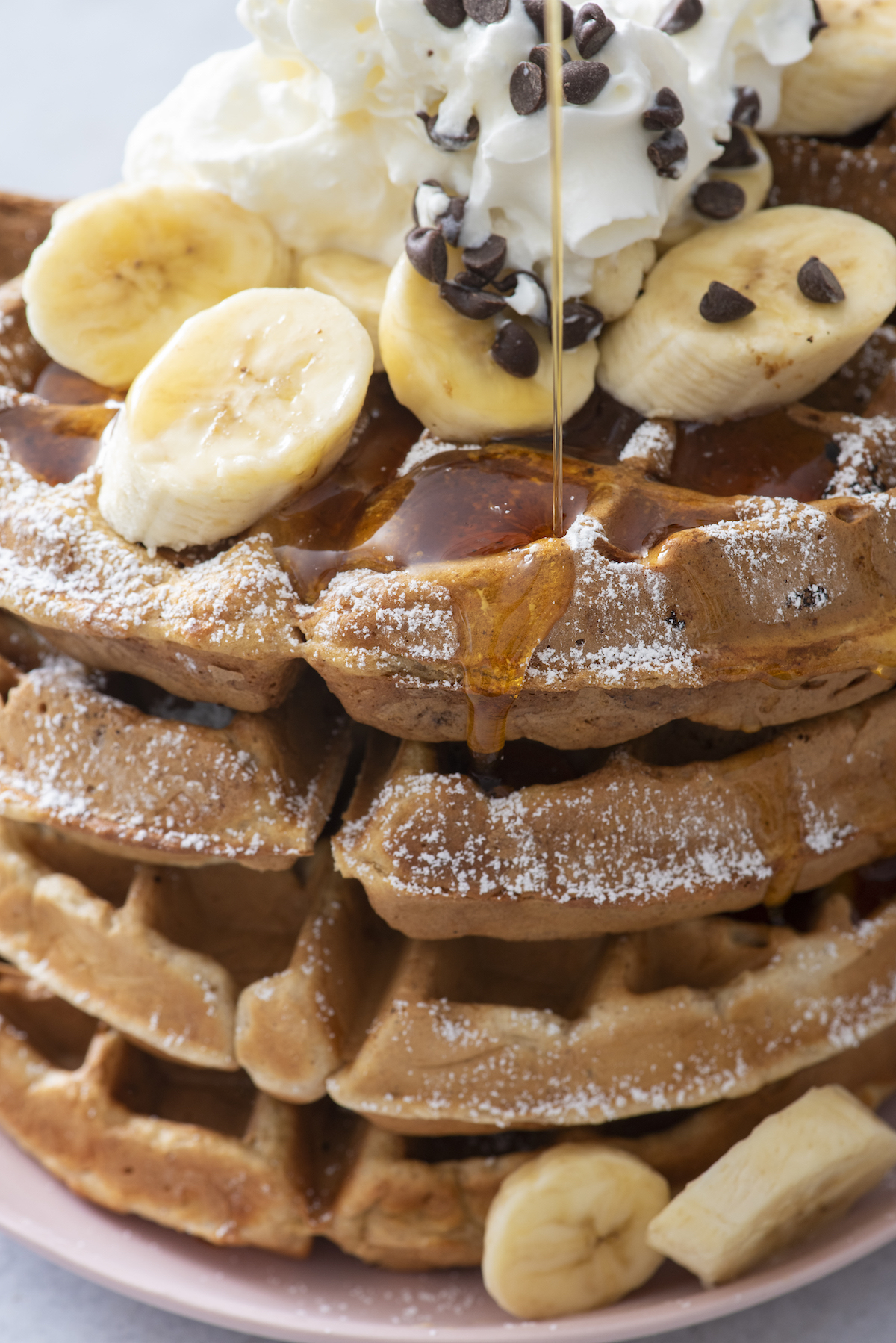 drizzling syrup over stack of waffles