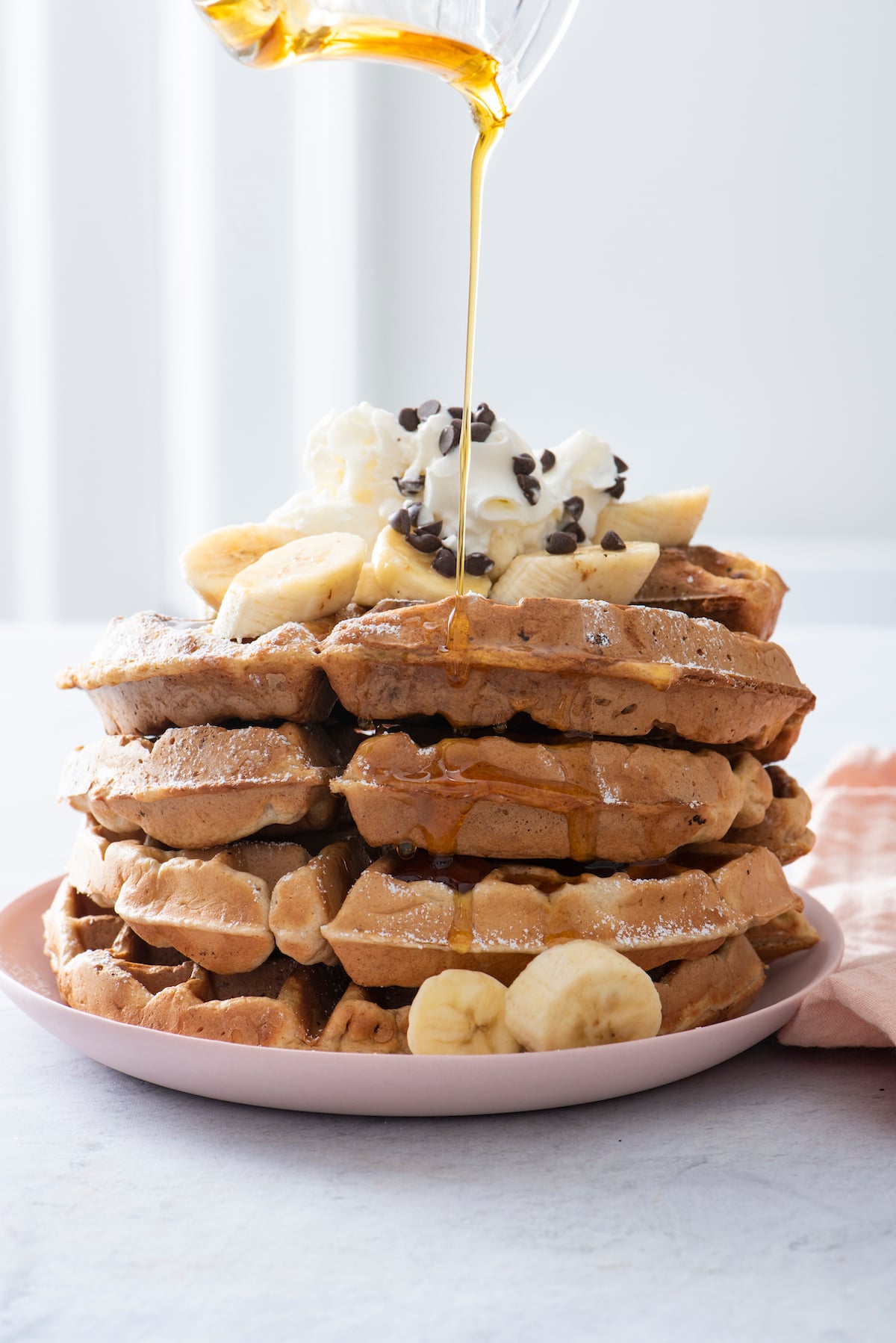 syrup pouring over stack of banana waffles