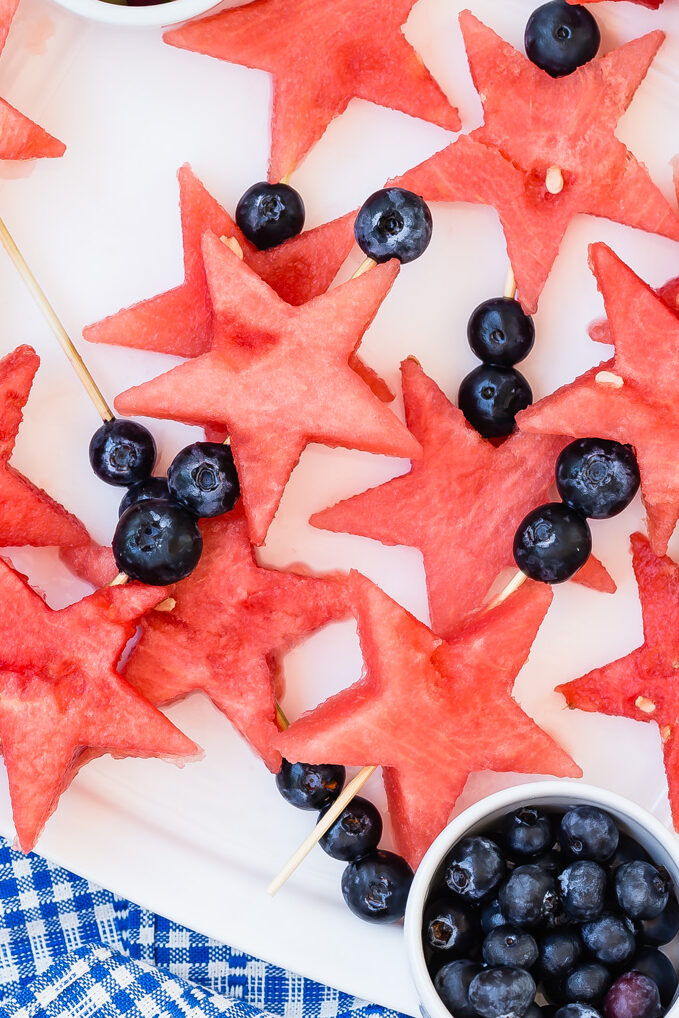 Star shaped watermelon chunks and blueberries on wooden skewers.