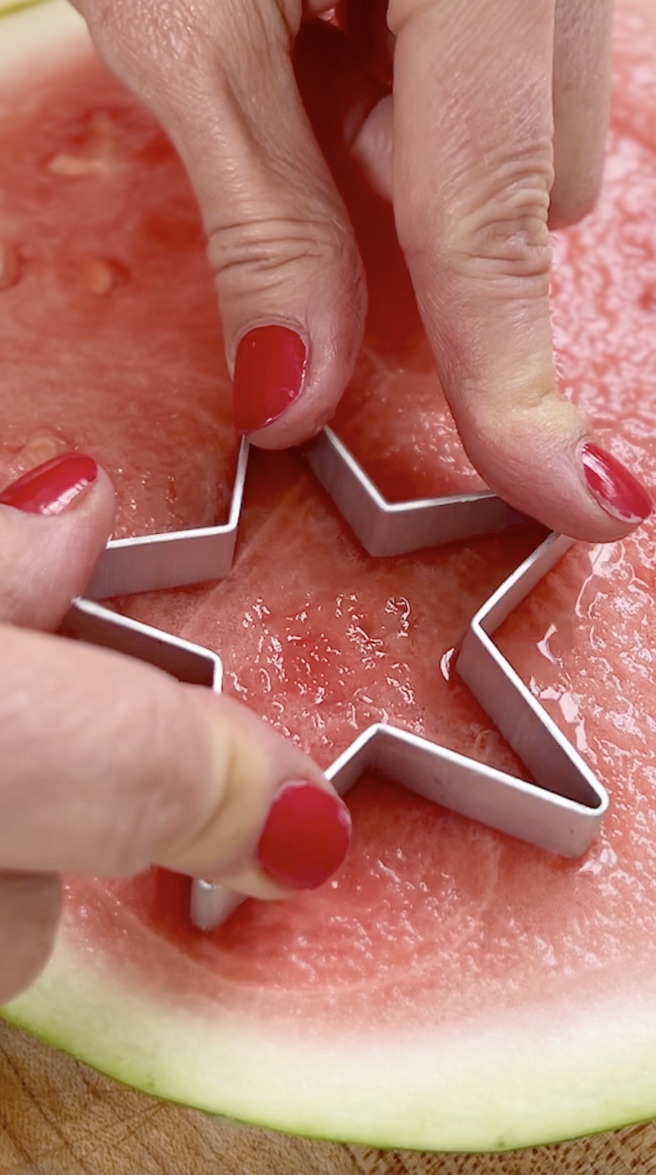 Cutting out a star shape from watermelon using cookie cutter.