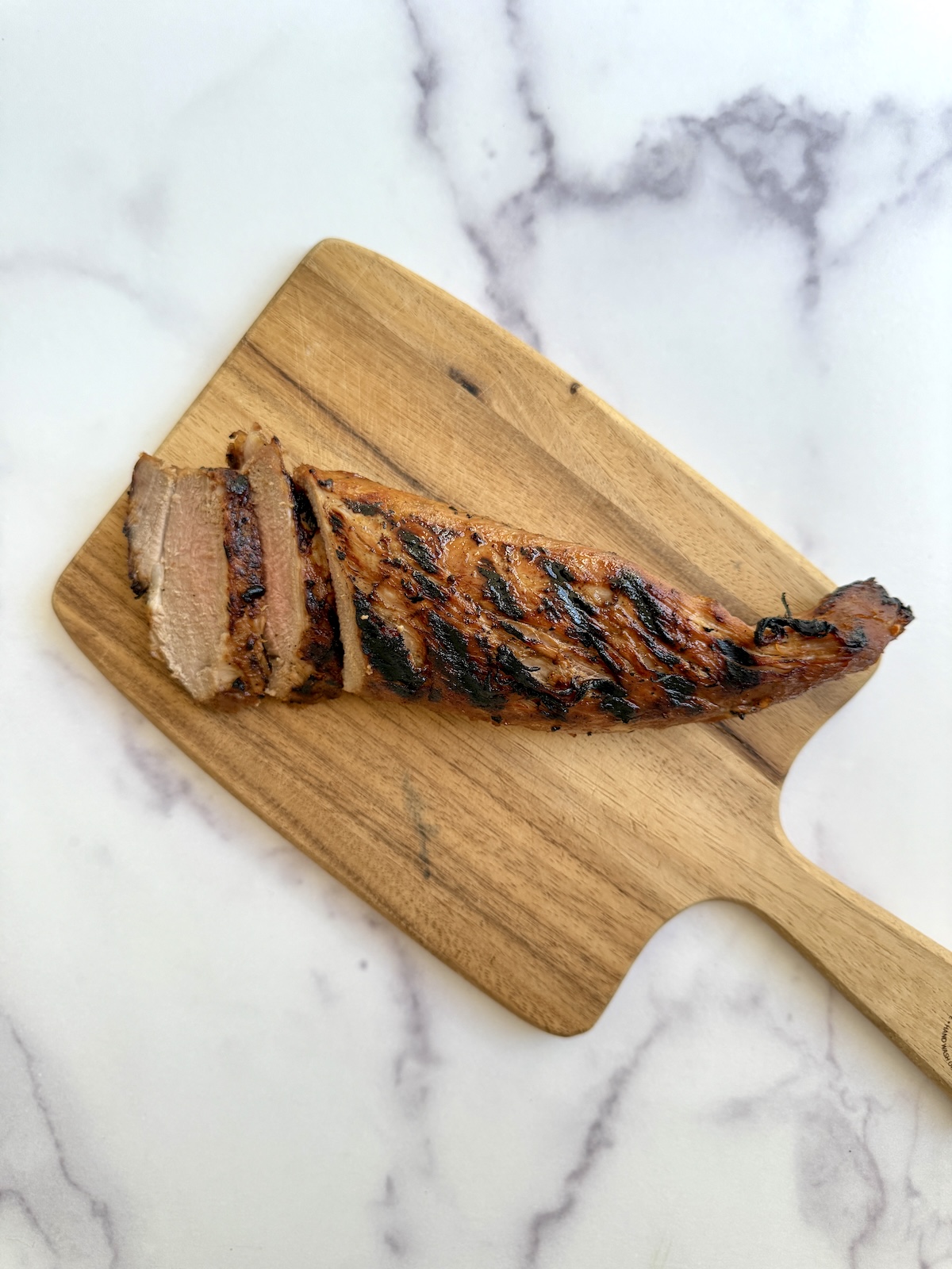 Grilled pork tenderloin on a cutting board.