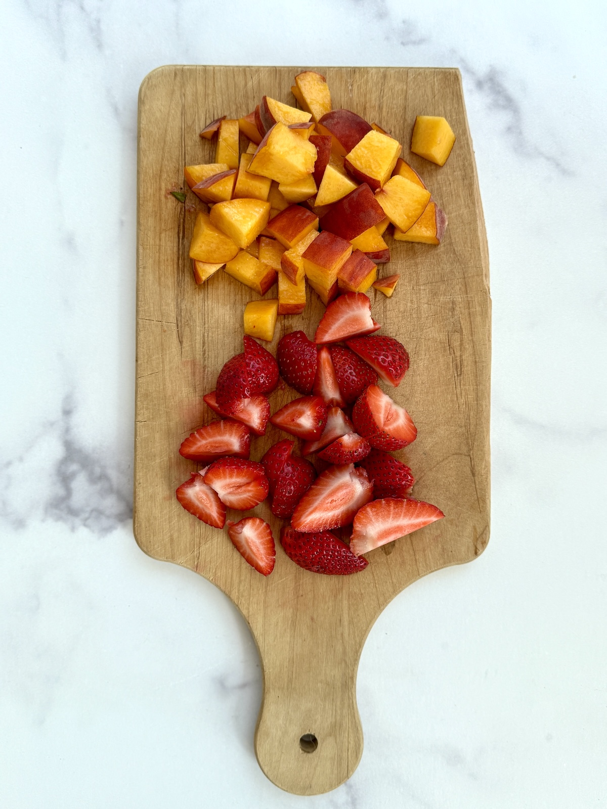 Cut up strawberries and peaches.