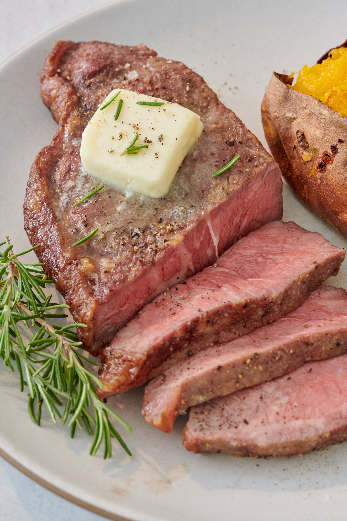 Air Fryer Steak topped with a knob of melting butter and fresh herbs.
