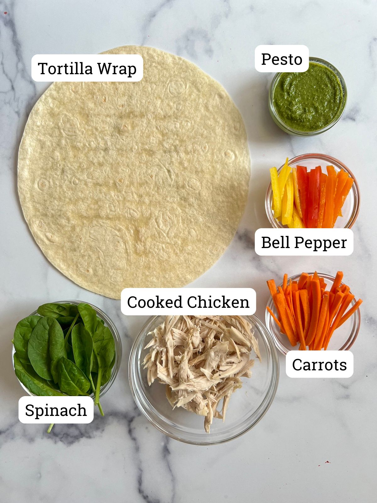 Chicken pesto wrap ingredients on a marble counter top.