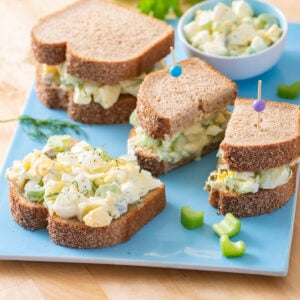 Egg salad sandwiches on blue serving platter.