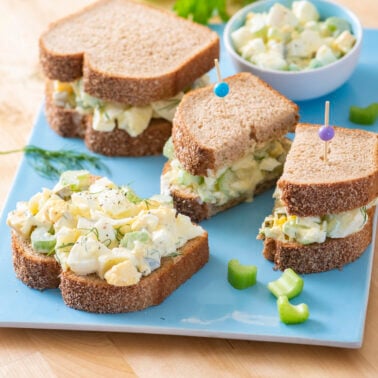 Egg salad sandwiches on blue serving platter.
