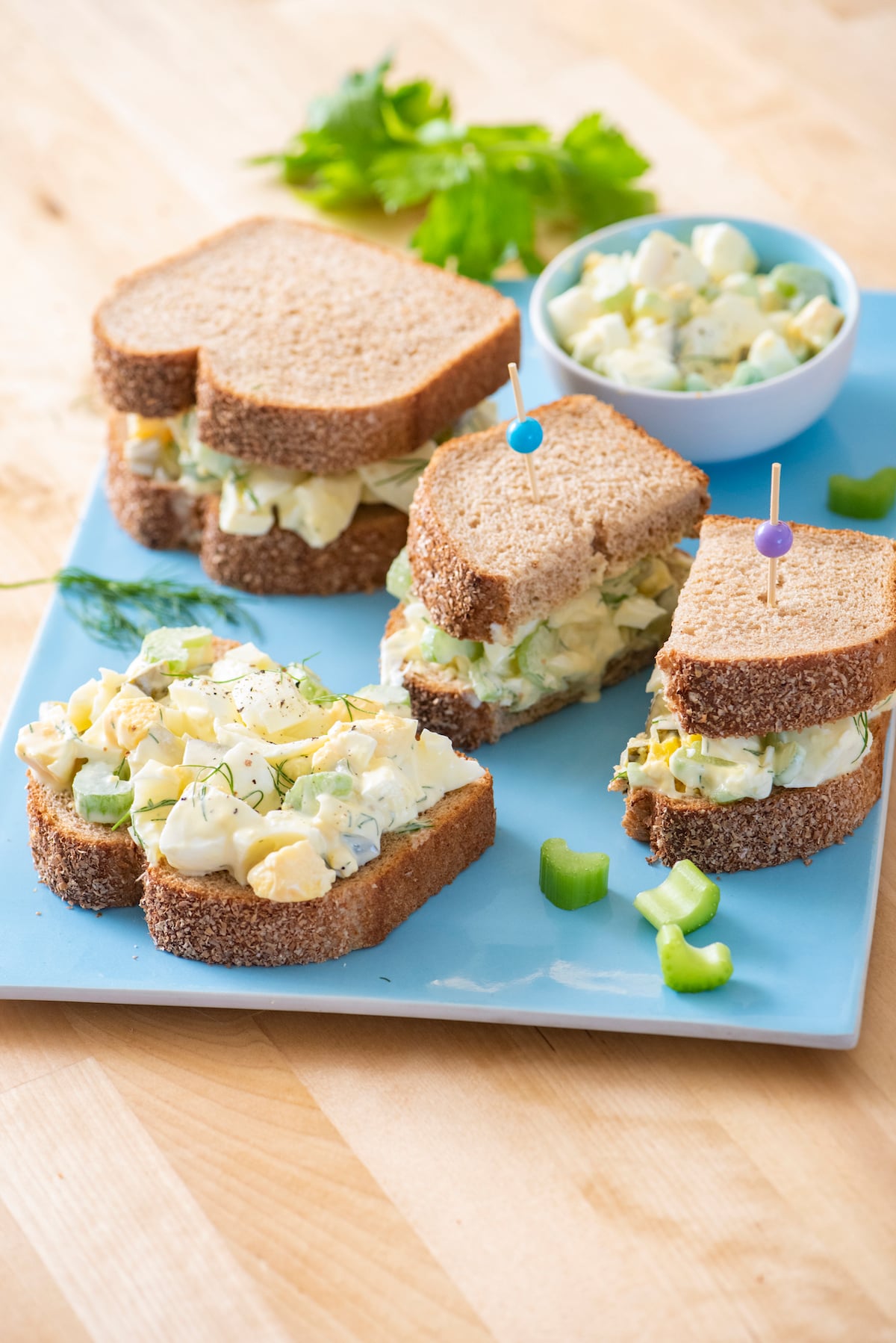 Egg salad sandwiches on blue serving platter.