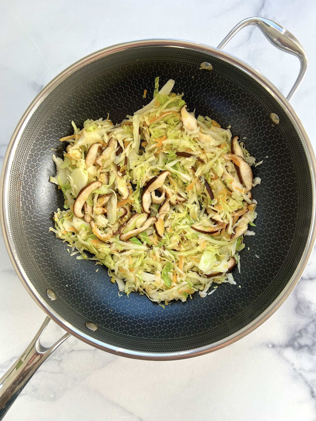 Sautéed cabbage and mushrooms in a pan.