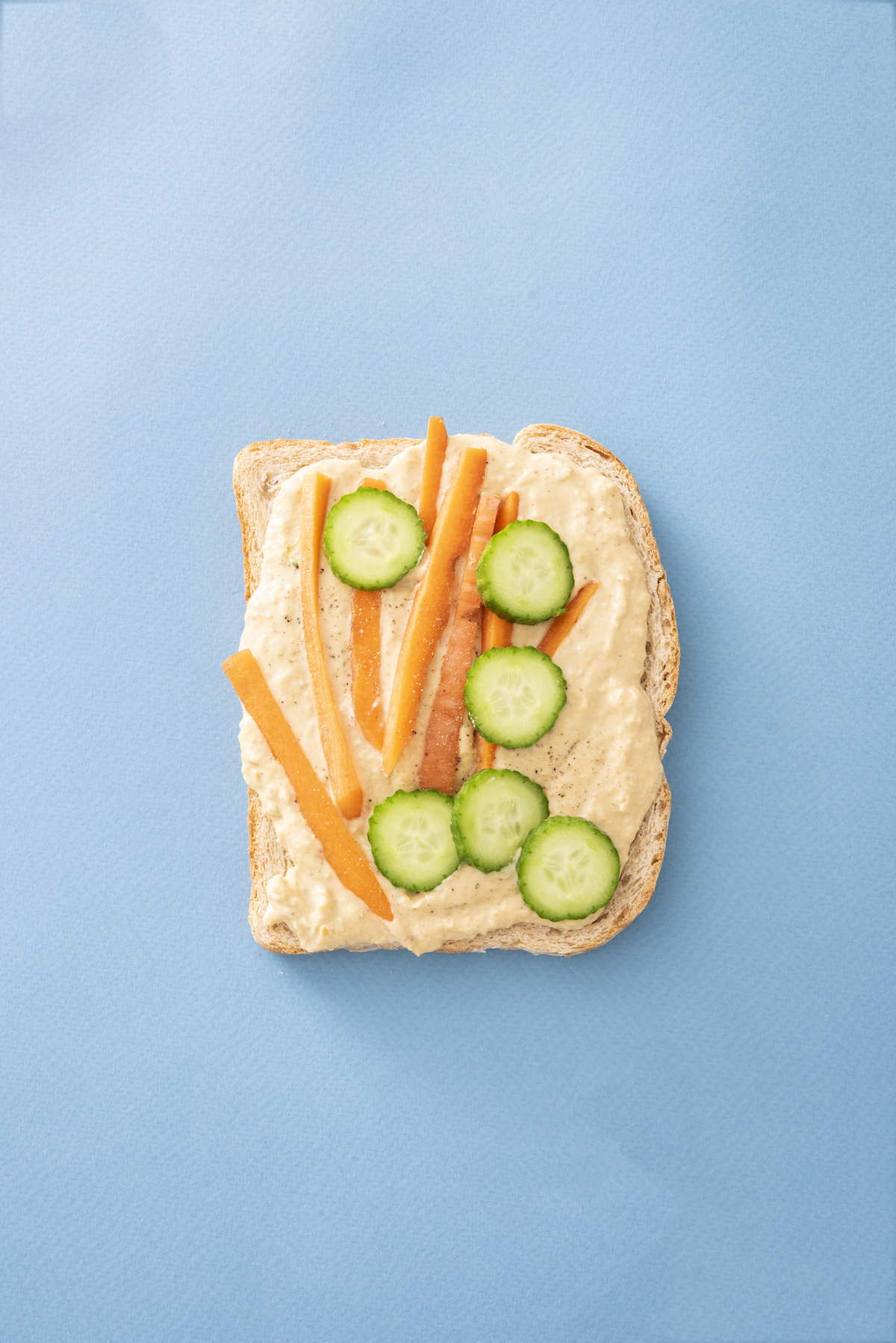 open face sandwich with hummus, carrots and cucumbers