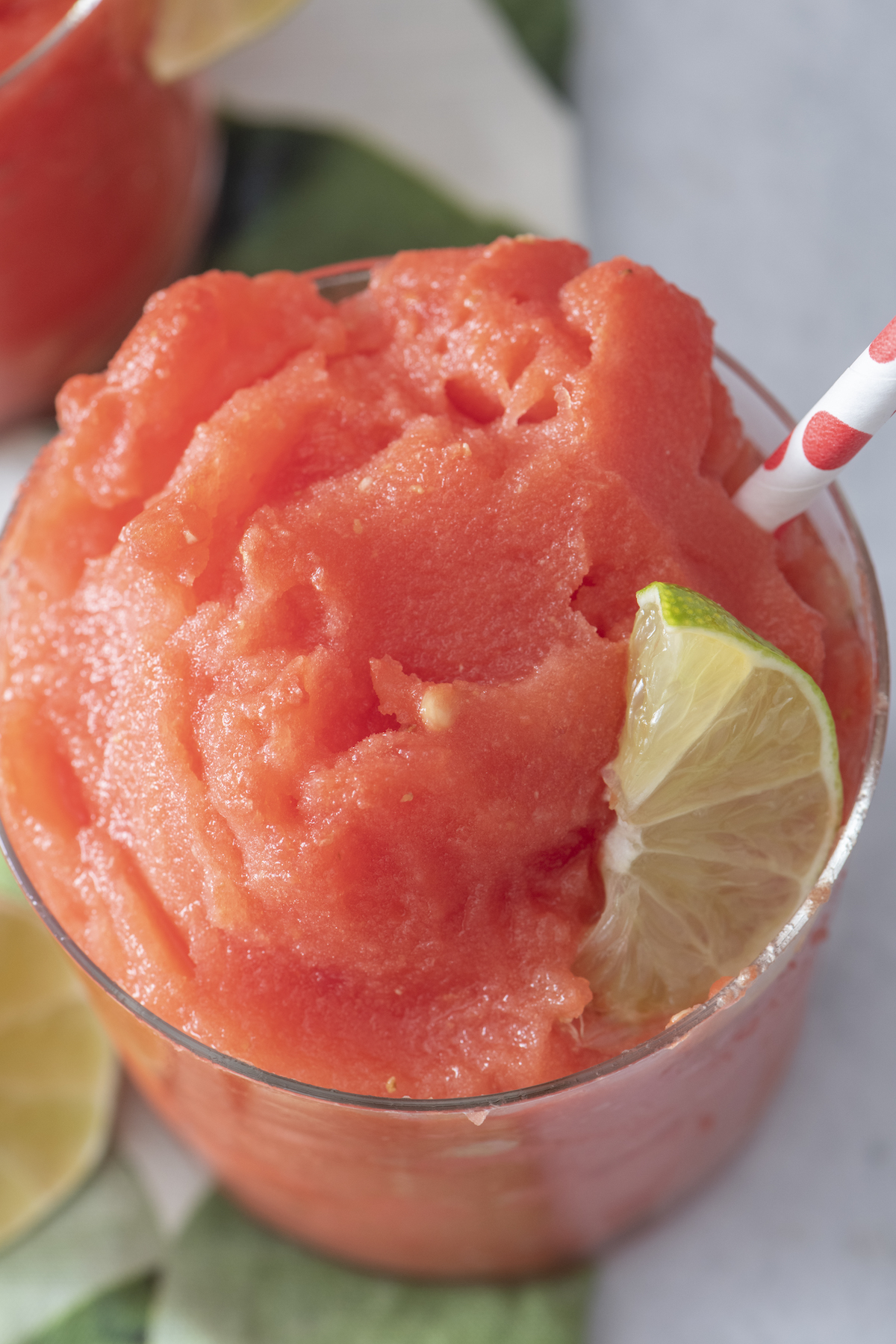 Watermelon slushie in a glass with a lime wedge.