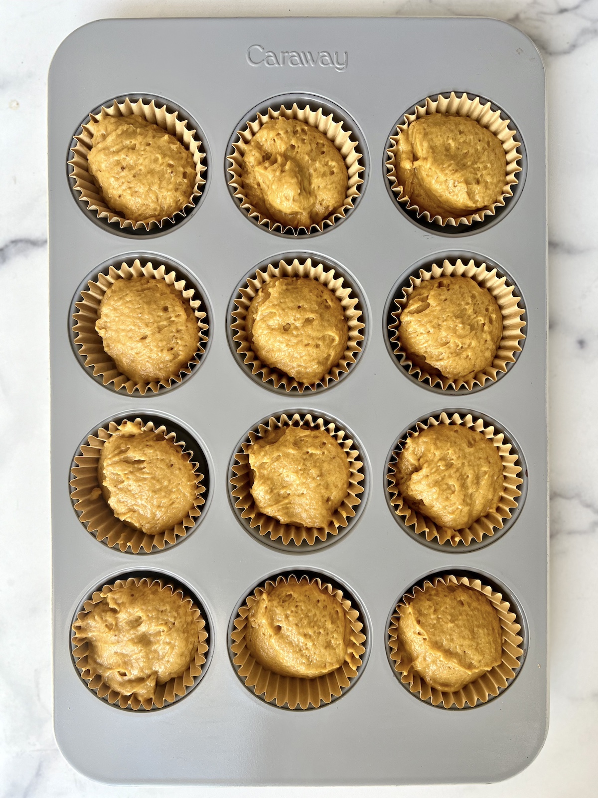 Pumpkin muffin batter in muffin cups ready to be baked.