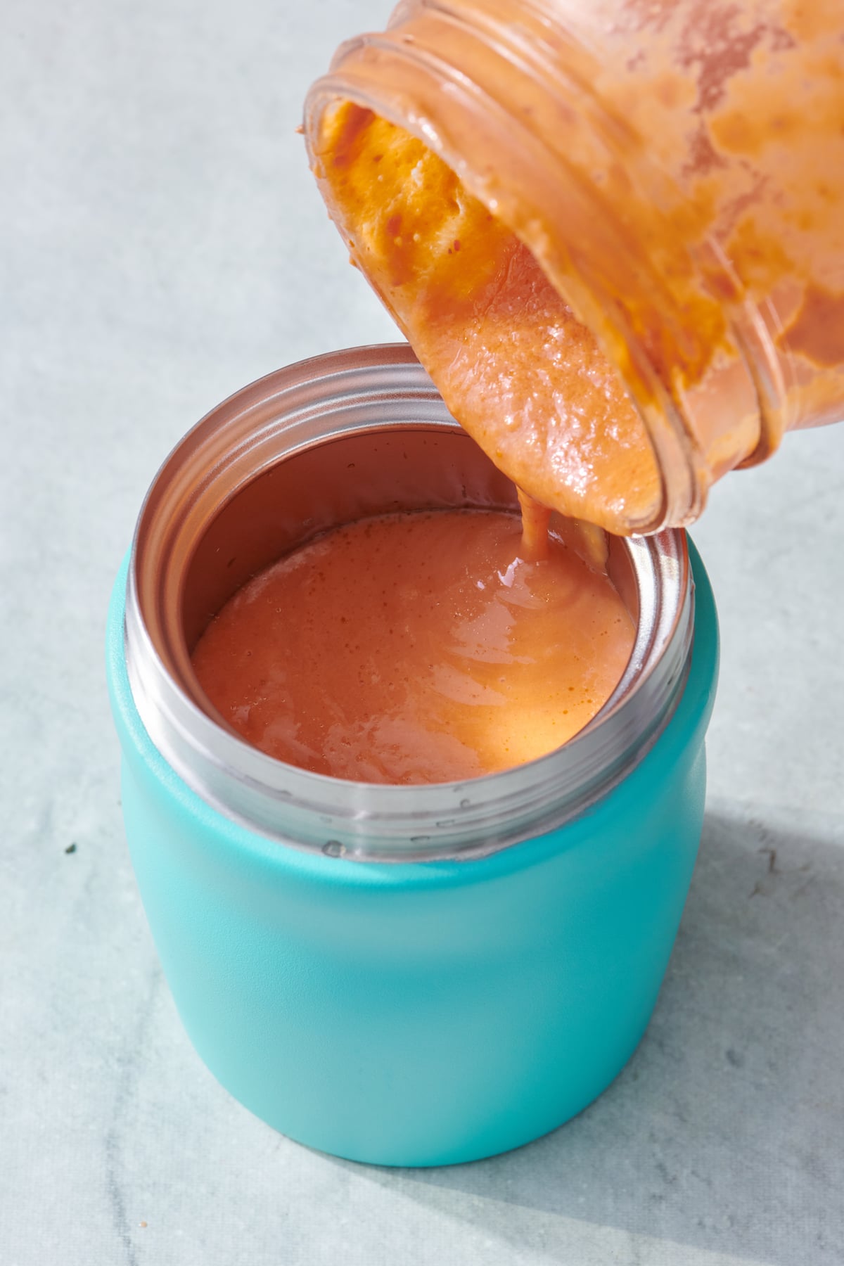 Pouring hot soup into a preheated thermos.