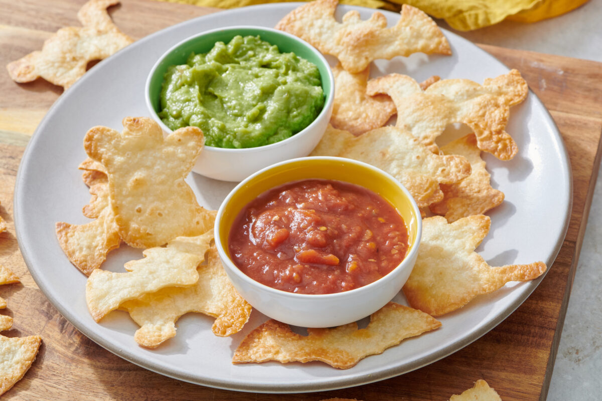Halloween tortilla chips on plate with salsa and guacamole.