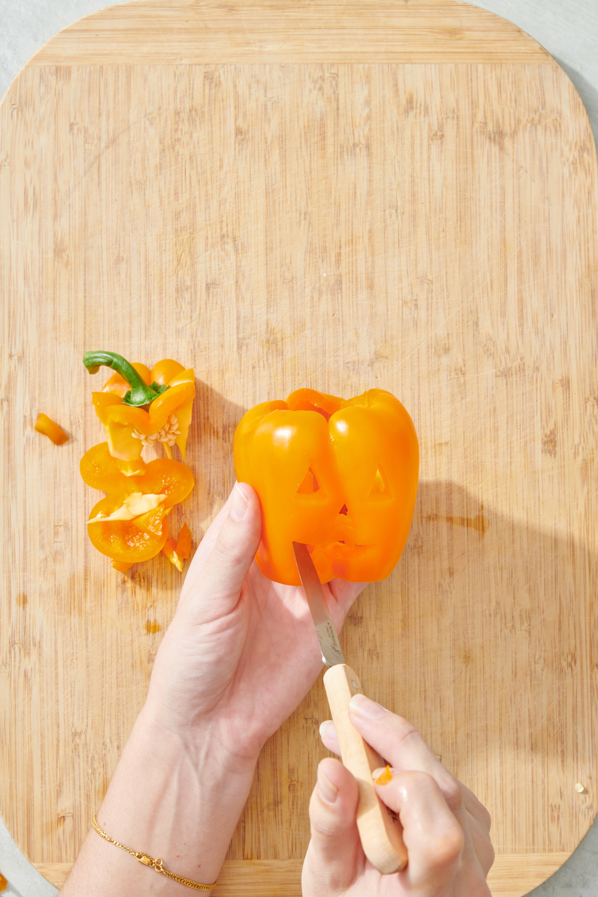 Carving jack-o'-lantern face into pepper.