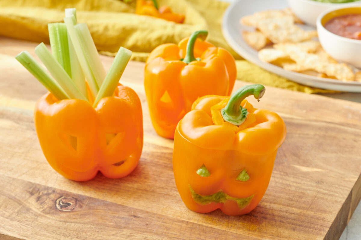 Jack-o'-lantern bell peppers on cutting board.