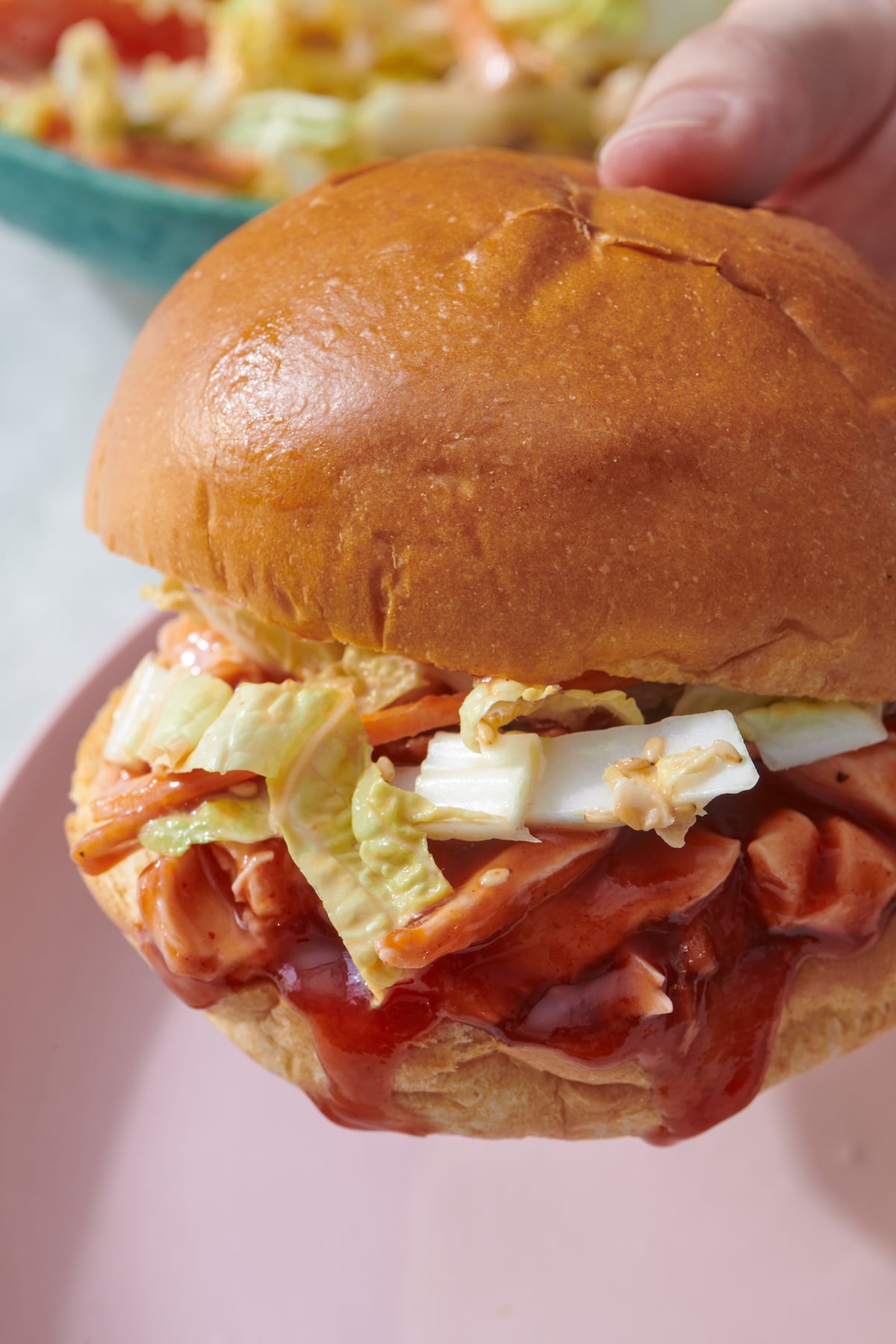 Hand holding BBQ chicken sandwich.