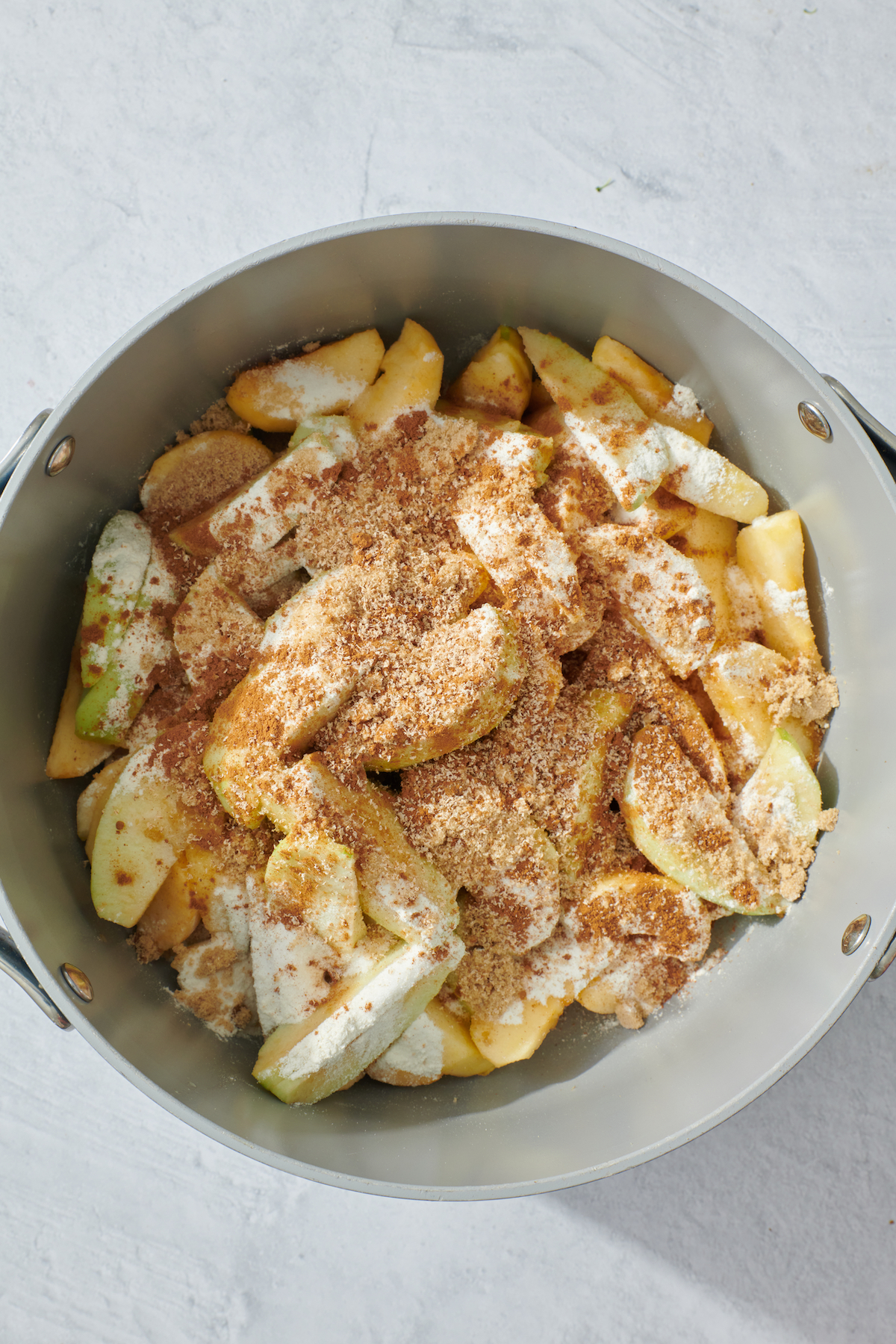 Sliced apples with sugar and flour in a pot.