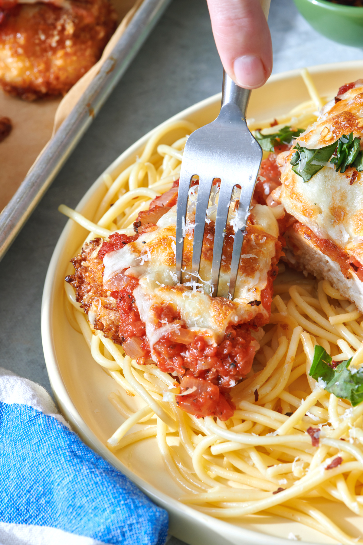 Fork piercing piece of chicken parmesan