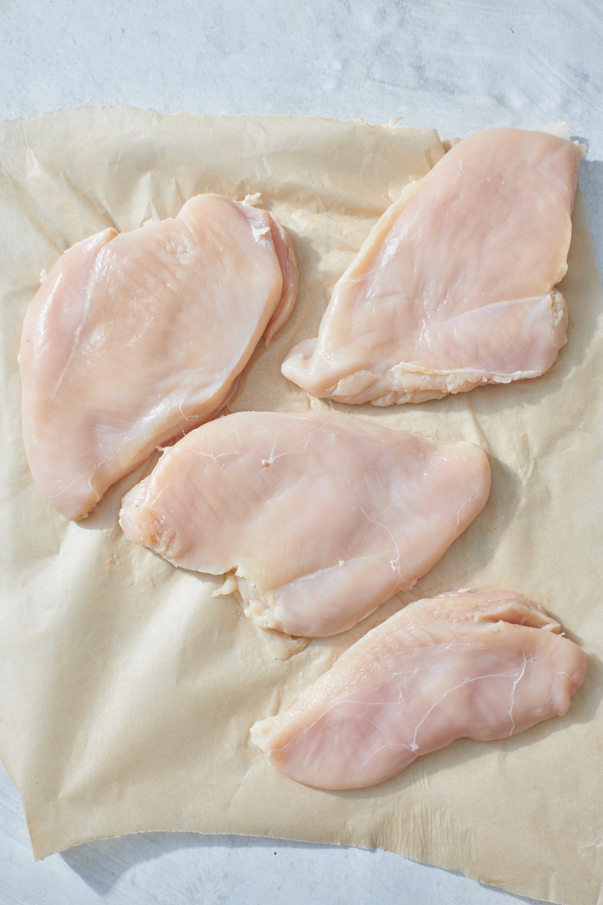 Flattened chicken breasts on parchment paper.