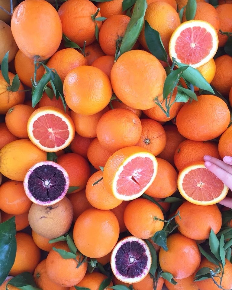 pile of oranges with some cut in half revealing bright purple and orange flesh