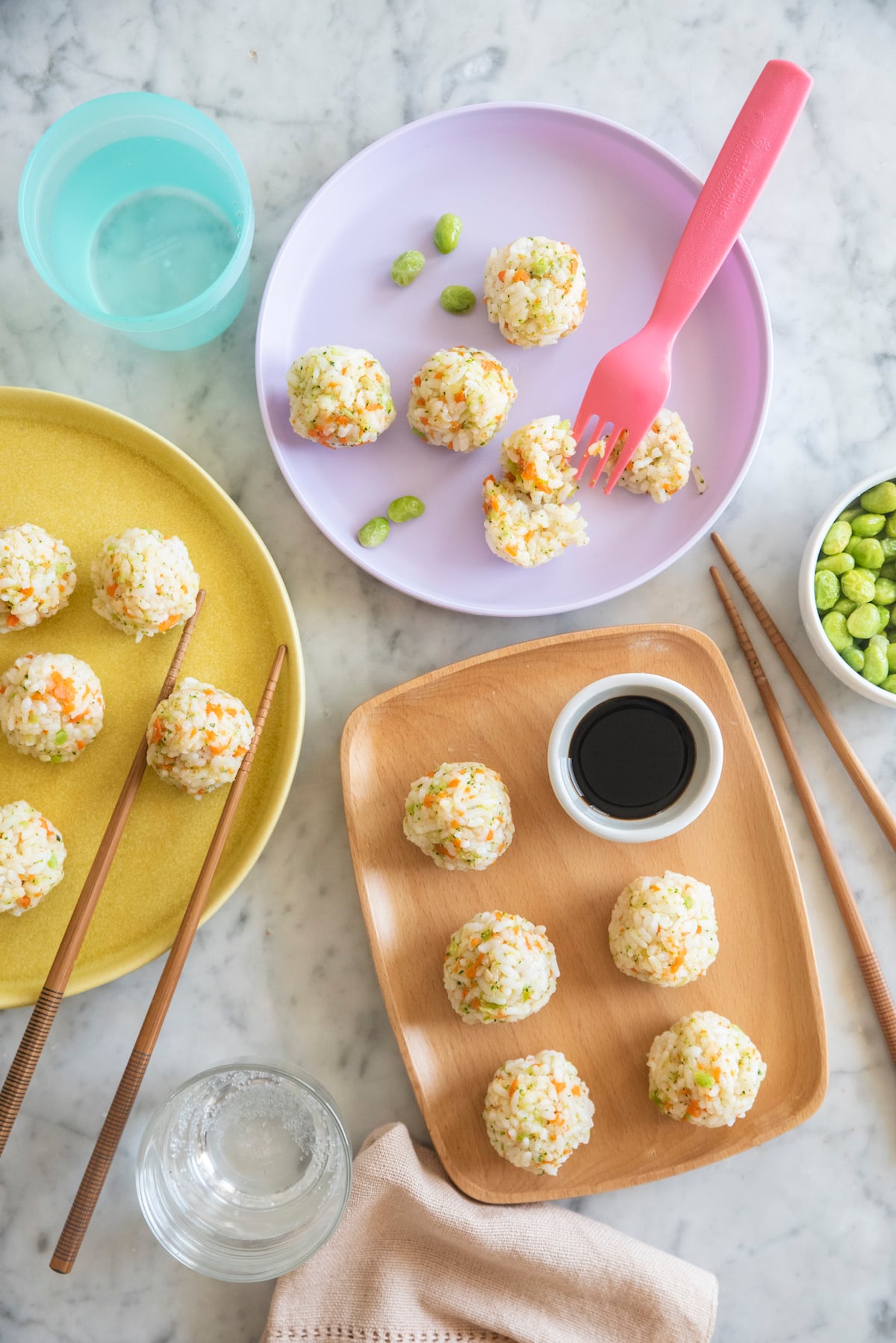 Japanese Rice Balls on small plates with chopsticks on the side.