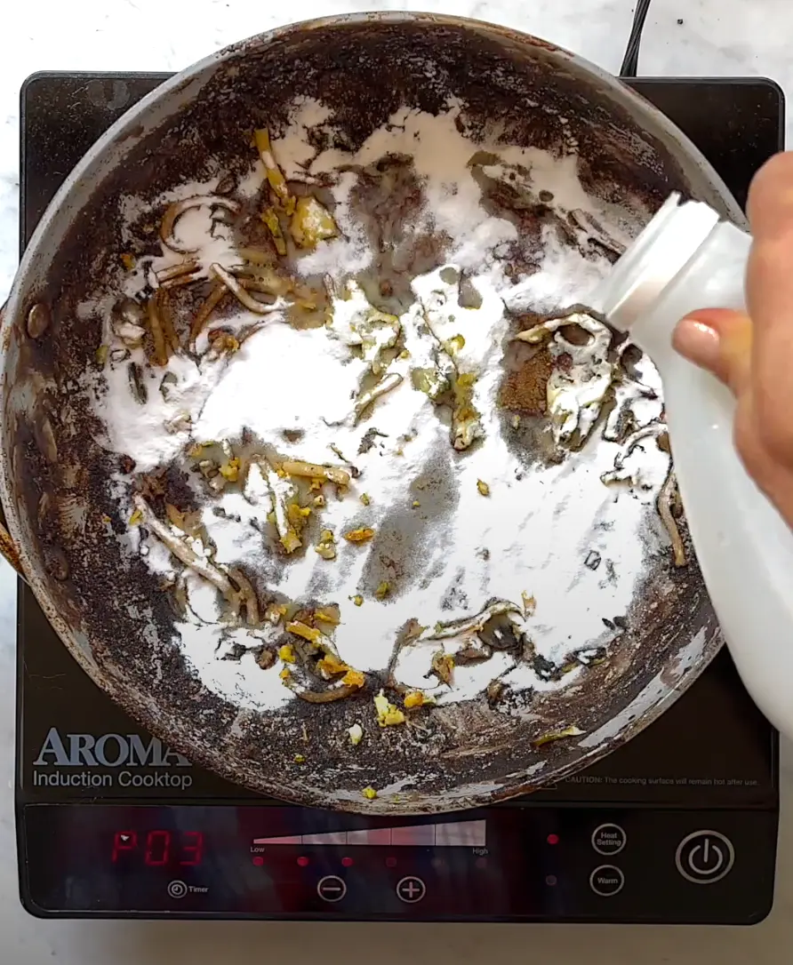 pouring vinegar over baking soda in dirty pan