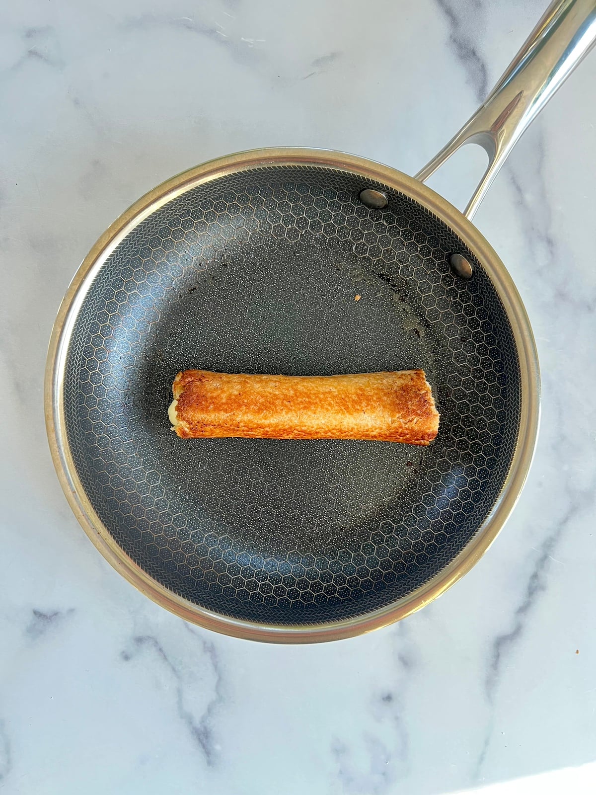 Grilled pizza roll up in a sauté pan.