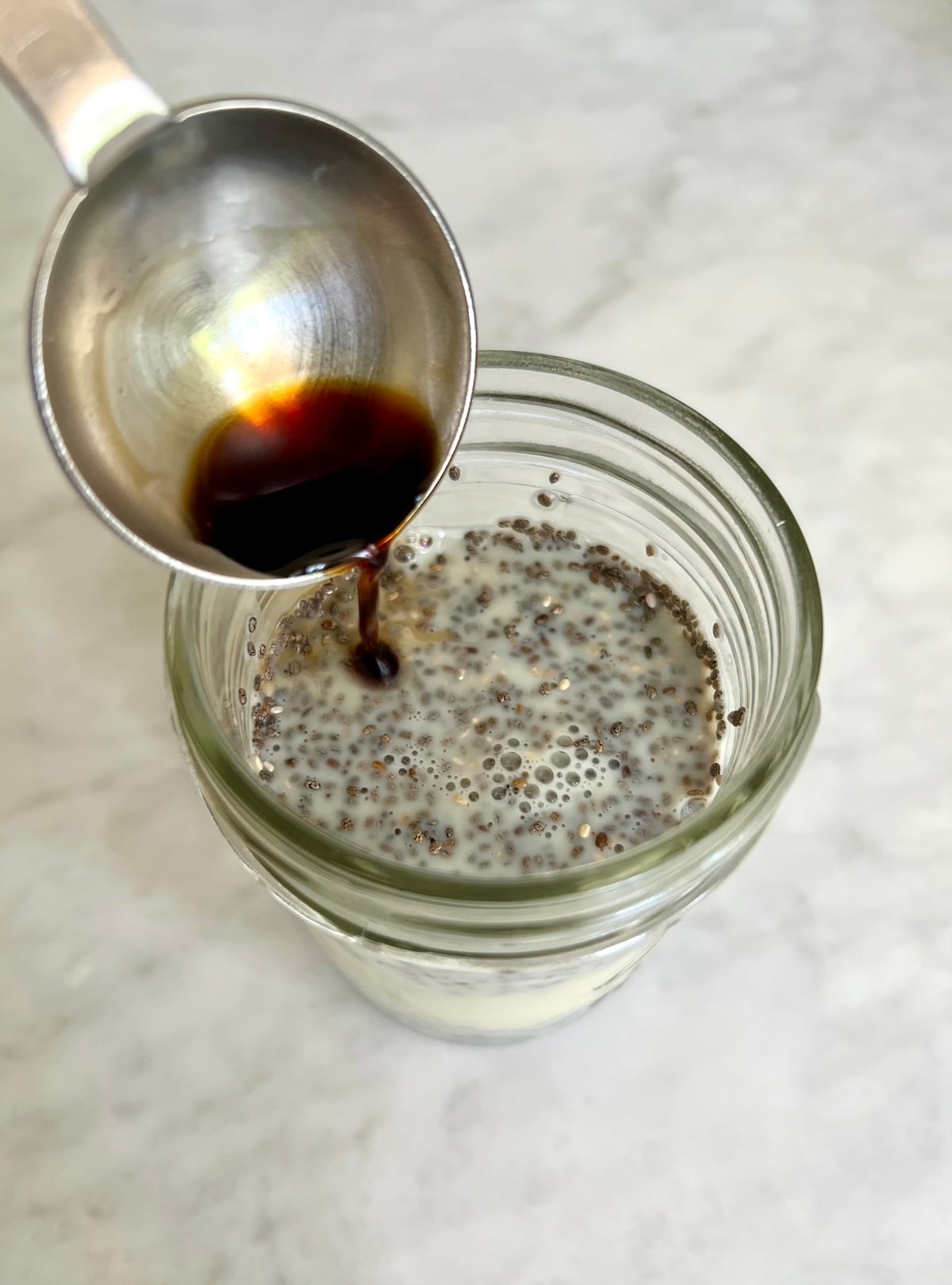 Pouring vanilla into chia seed pudding.