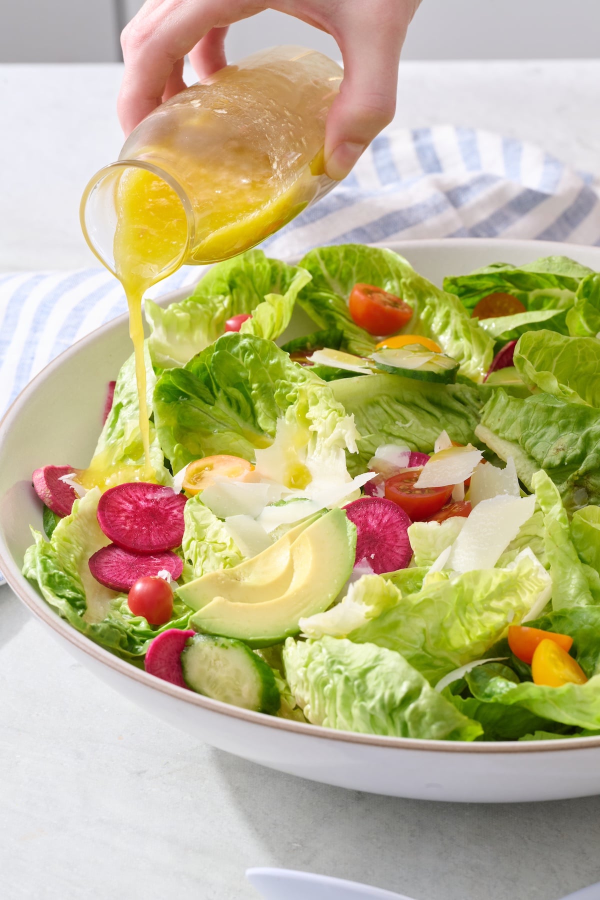Pouring lemon vinaigrette over salad.