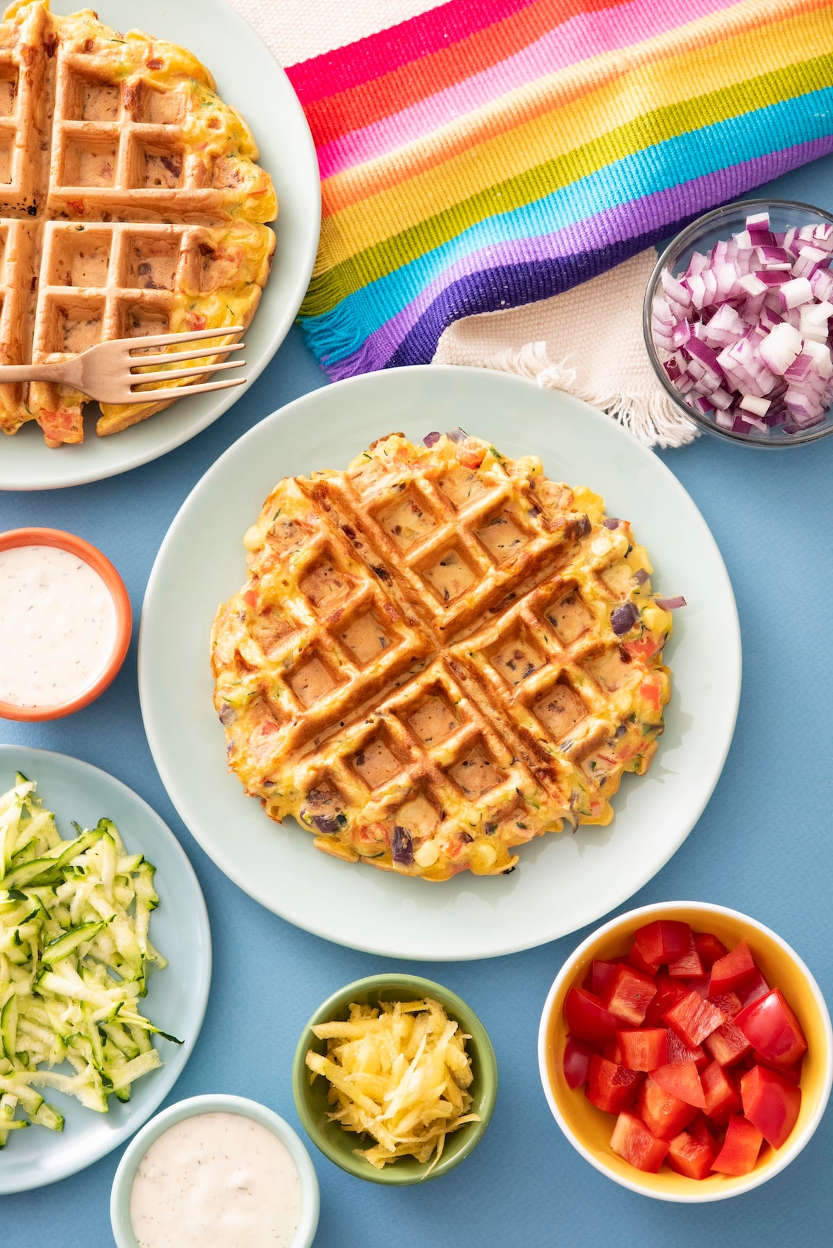 Rainbow Waffle on plate with vegetables surrounding.