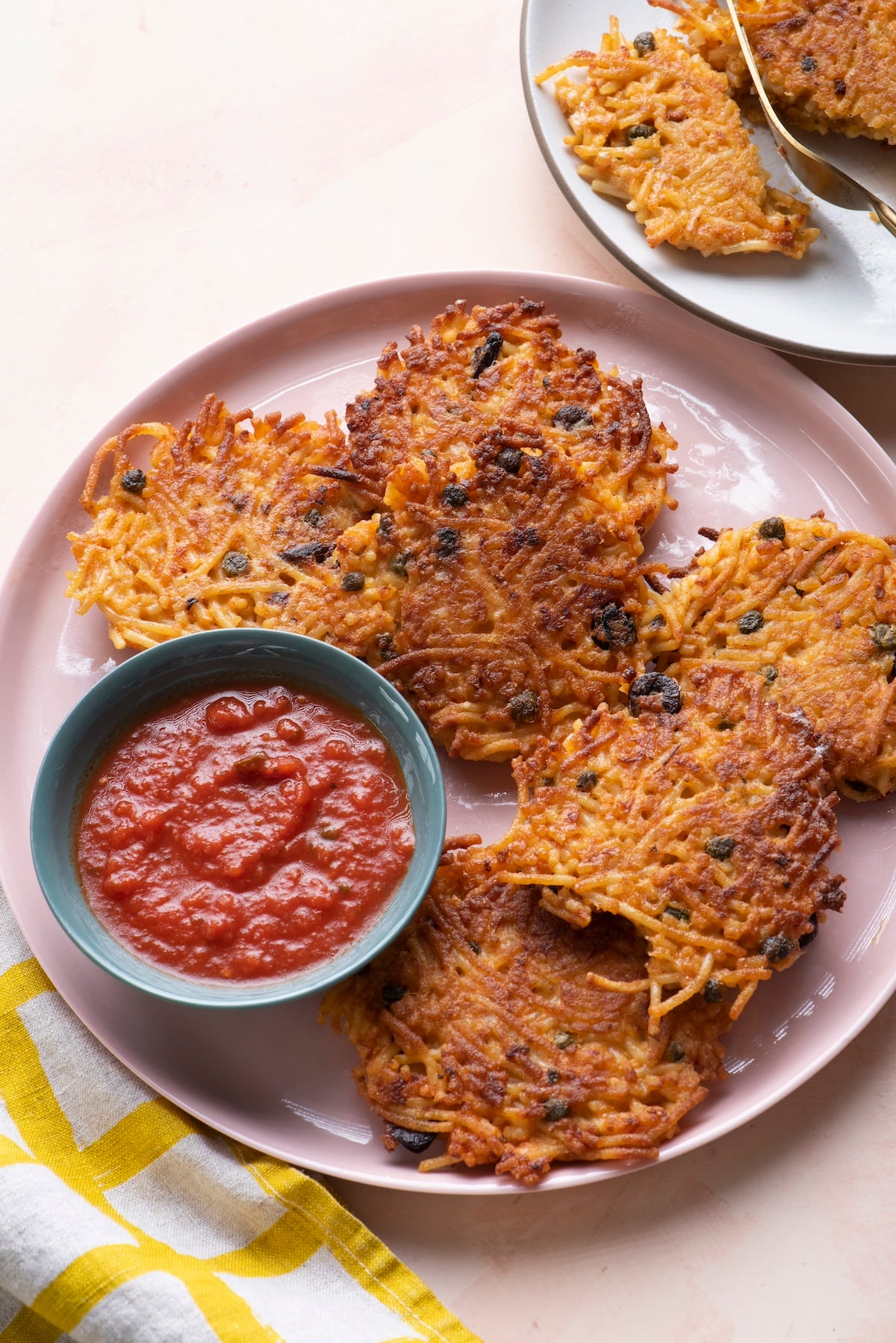 Spaghetti Cake fritters on pink serving platter with a side of marinara.