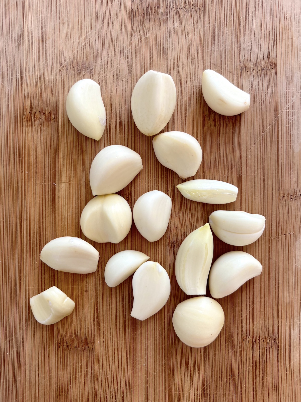 Peeled garlic on a cutting board.