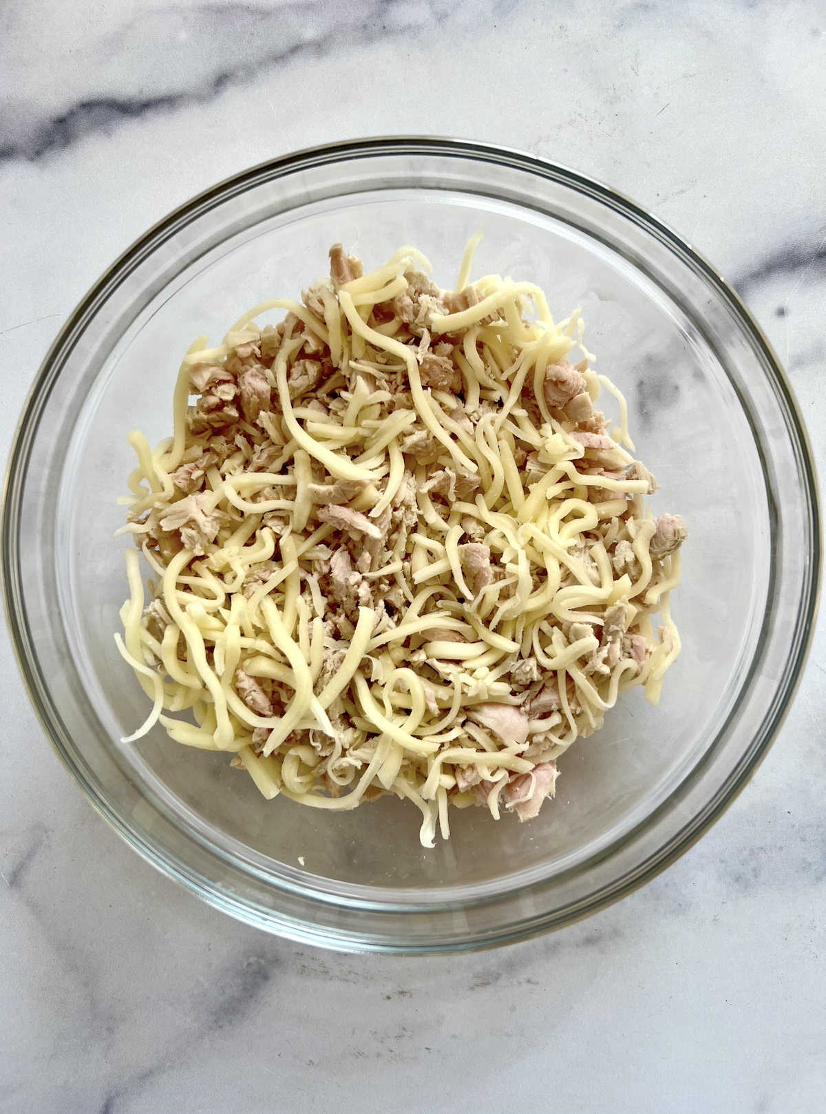 A bowl of roast turkey and shredded cheese.