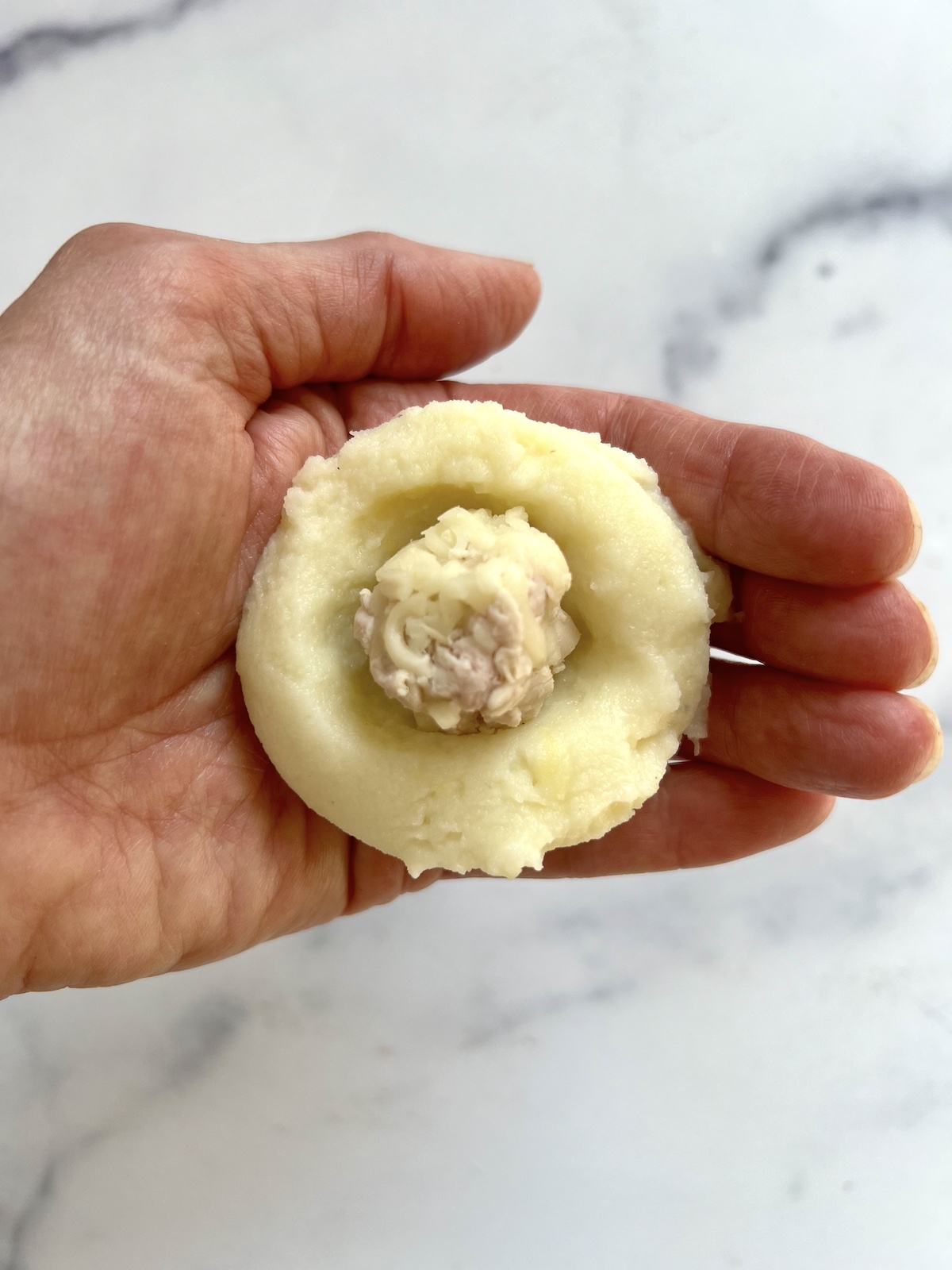 Wrapping turkey ball in mashed potatoes.