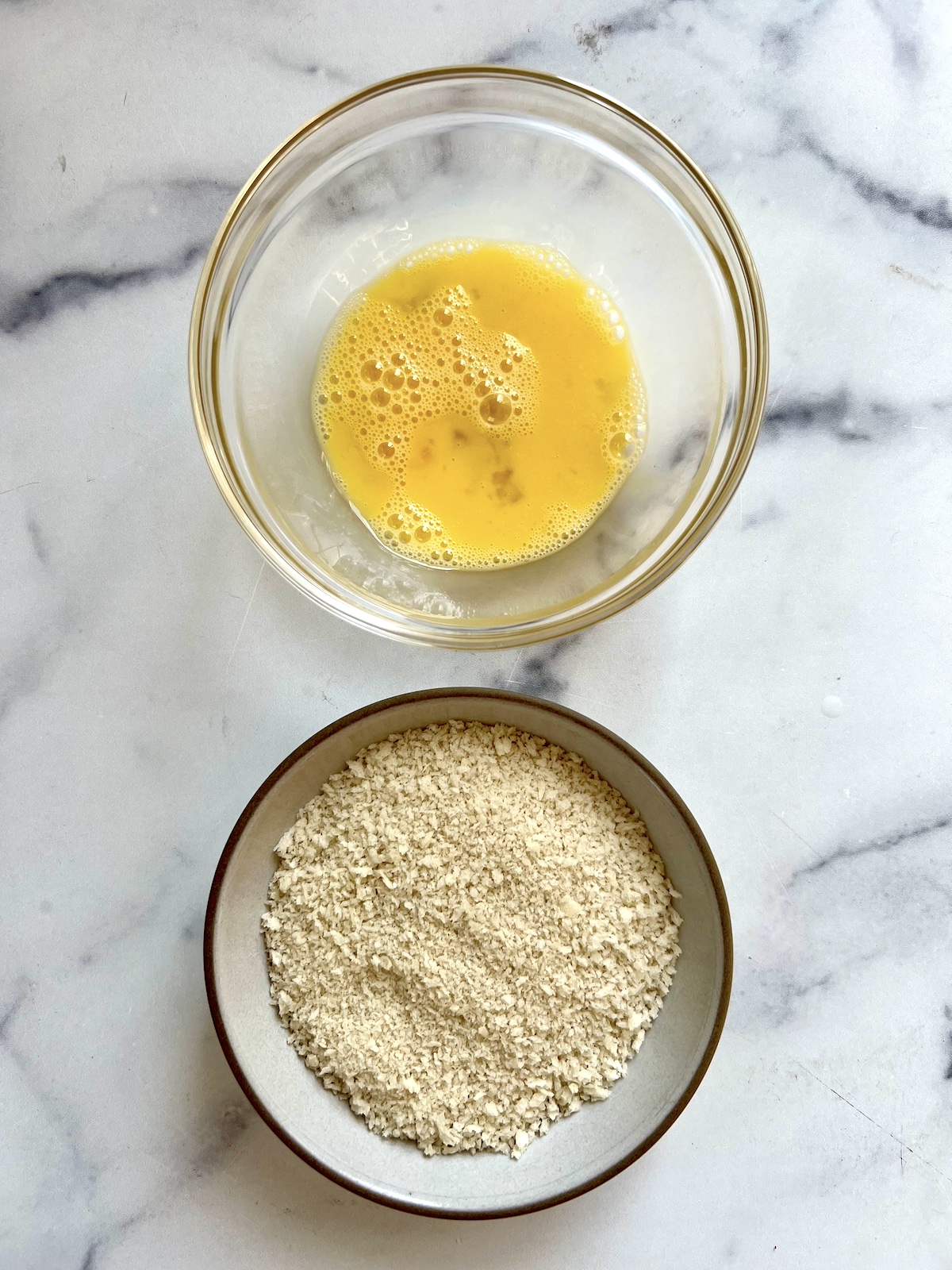 Bowls of breadcrumbs and whisked eggs.
