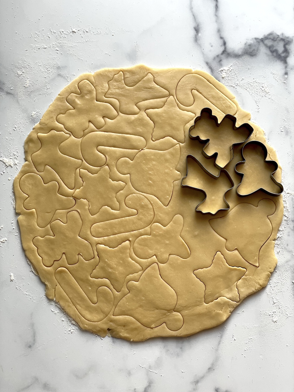 Using cookie cutters to cut shapes out of dough.