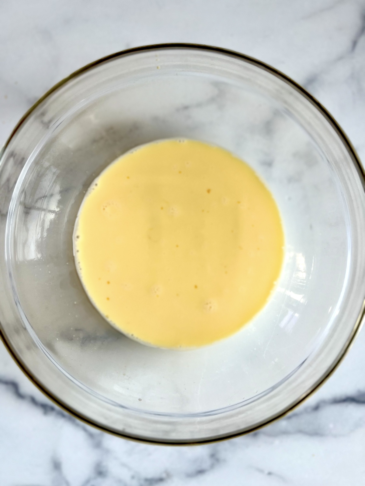 Milk and eggs whisked in a bowl.