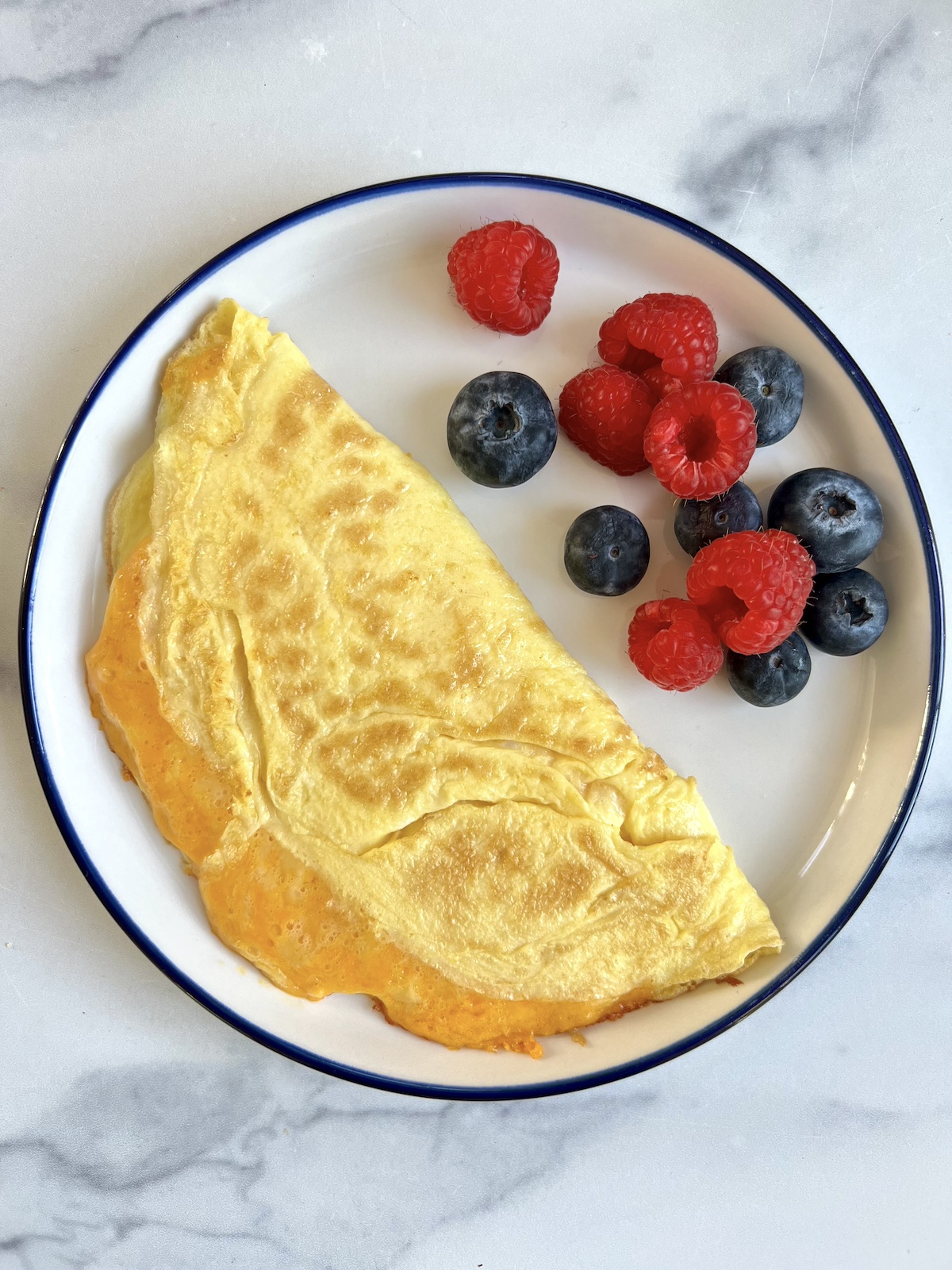 Cheese omelette and fruit on a plate.