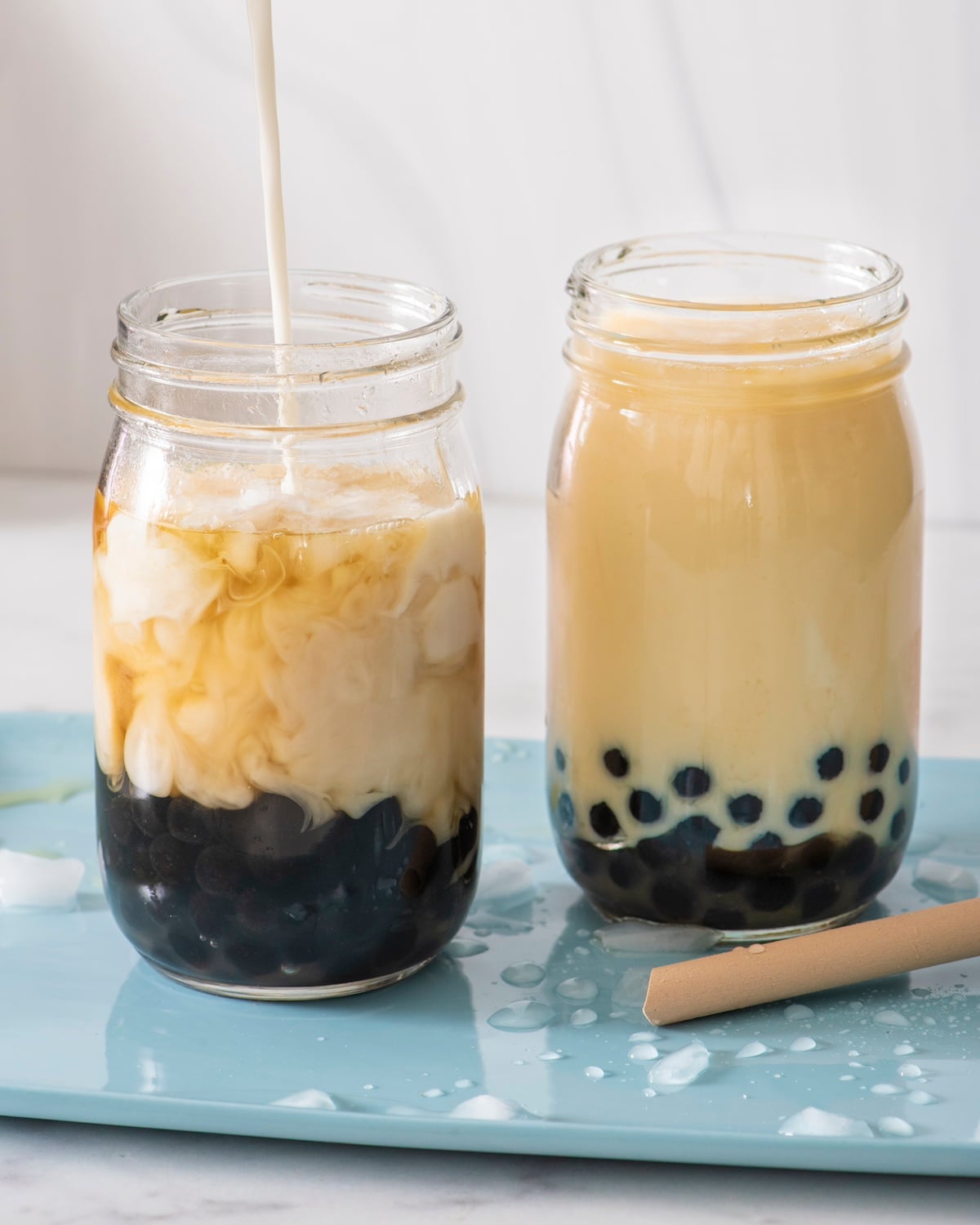 Pouring milk into glass of bubble tea.