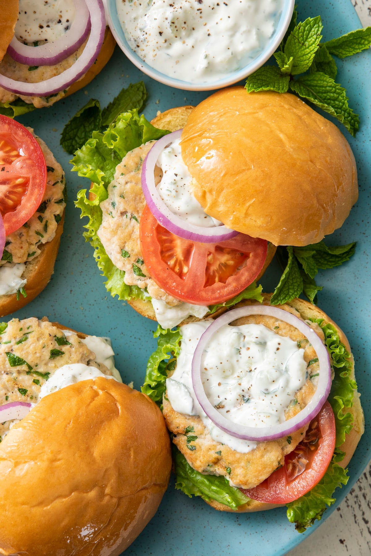Middle Eastern Chicken Burgers topped with cucumber yogurt sauce.