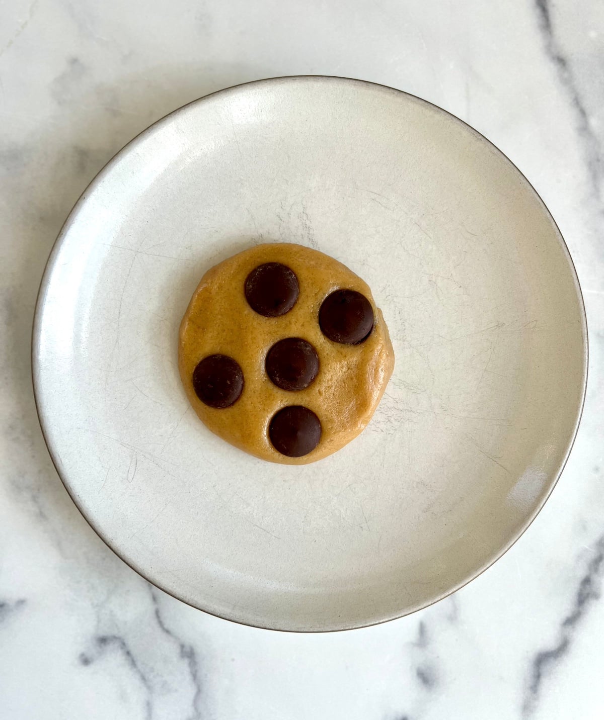 Chocolate chip cookie dough on a plate ready to microwave.