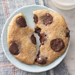 Microwave chocolate chip cookie broken in half on a plate.