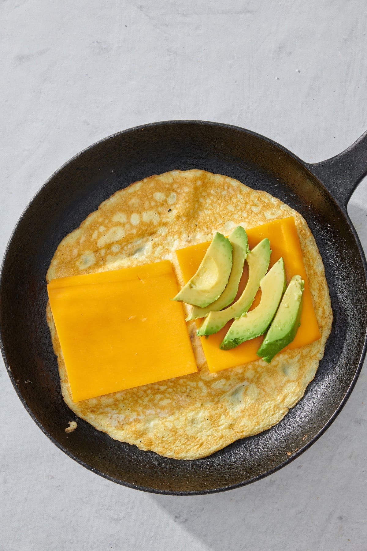 Sliced cheese and avocado layered on top of eggs.