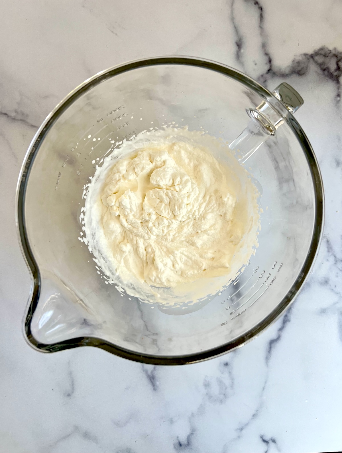 Whipped heavy cream in a mixing bowl.