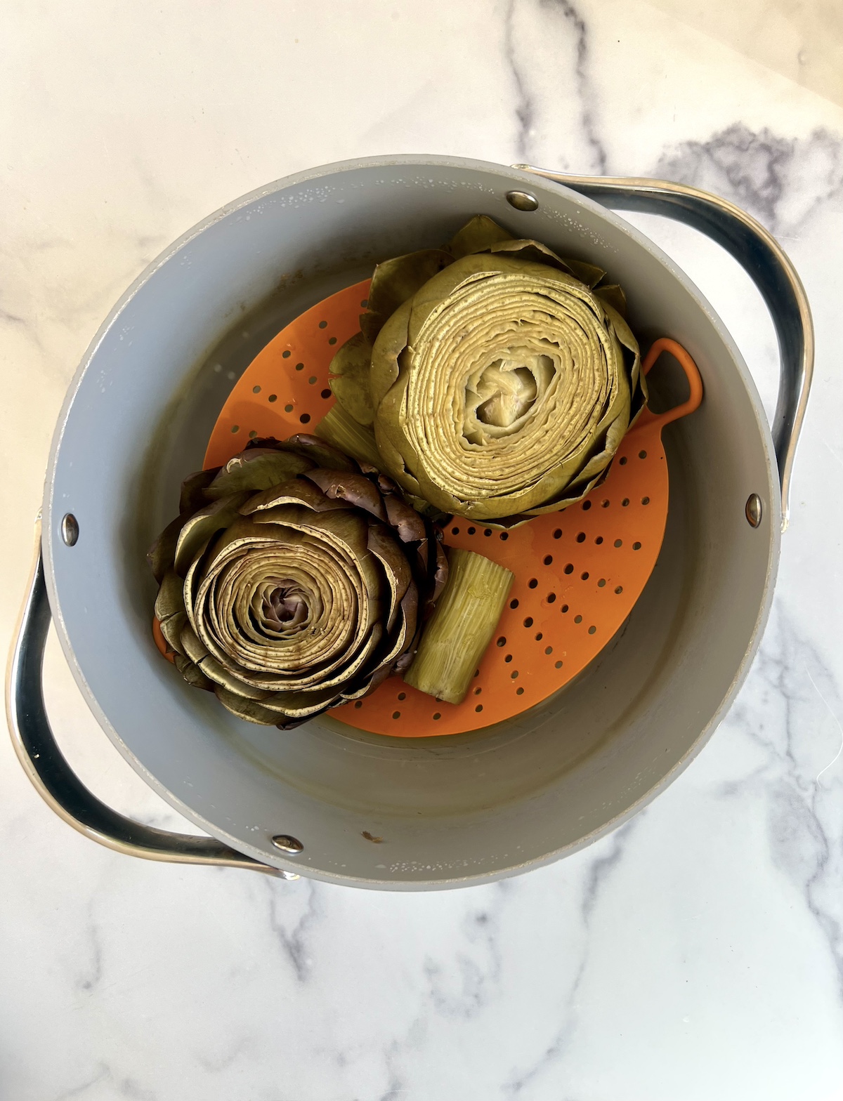 Steamed artichokes in a pot.